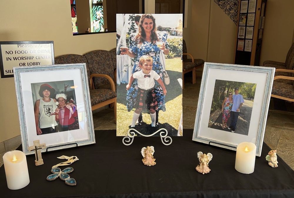 A memorial display featuring framed photographs and angel figurines on a table.