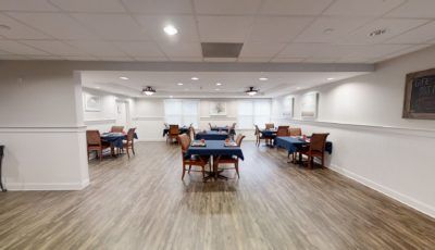 A spacious dining area with neatly arranged tables and chairs on a wooden floor.