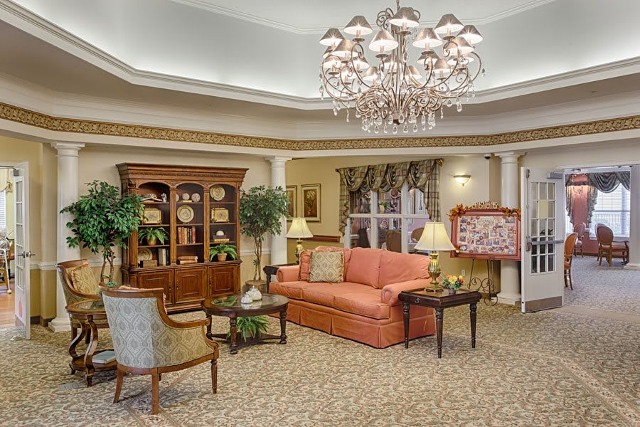 A tastefully decorated living room with a large chandelier, comfortable seating, and elegant furnishings.