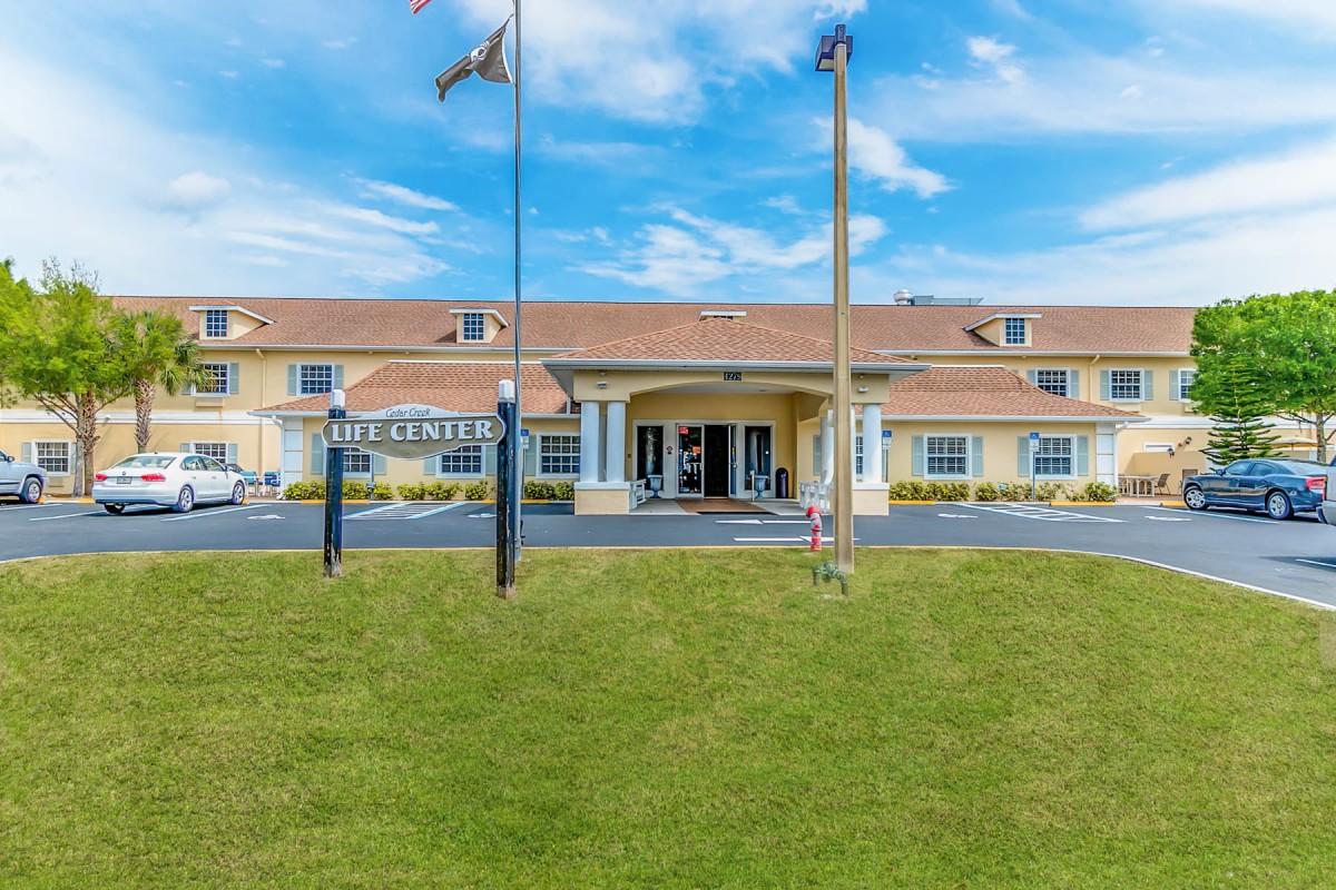 A hotel building with a welcoming entrance, surrounded by flags under a cloudy sky.