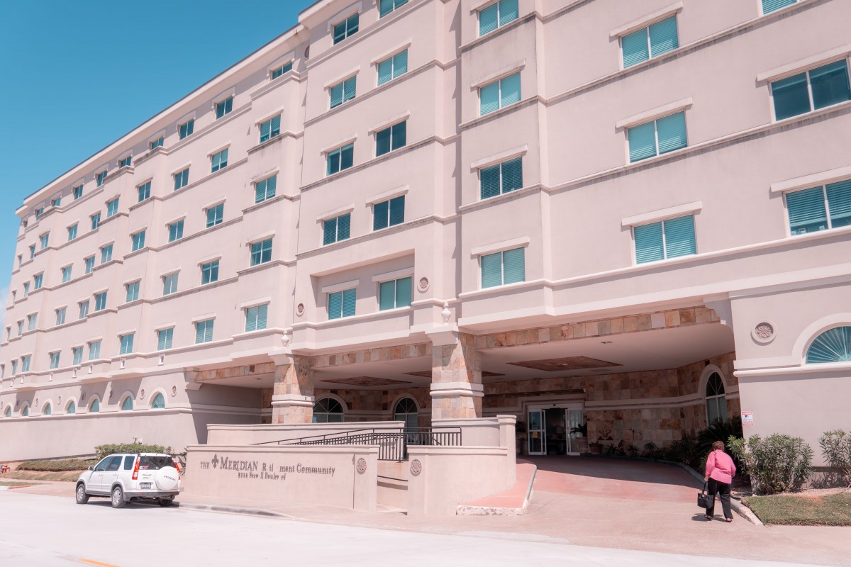 A modern hotel building with multiple floors and an entrance area with parked cars.