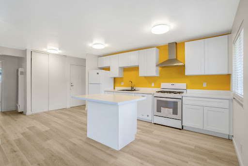A bright and modern kitchen featuring white cabinetry, a yellow accent wall, and a central island.