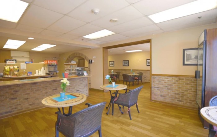 A cozy caf interior with tables and chairs, featuring bright lighting and welcoming decor.
