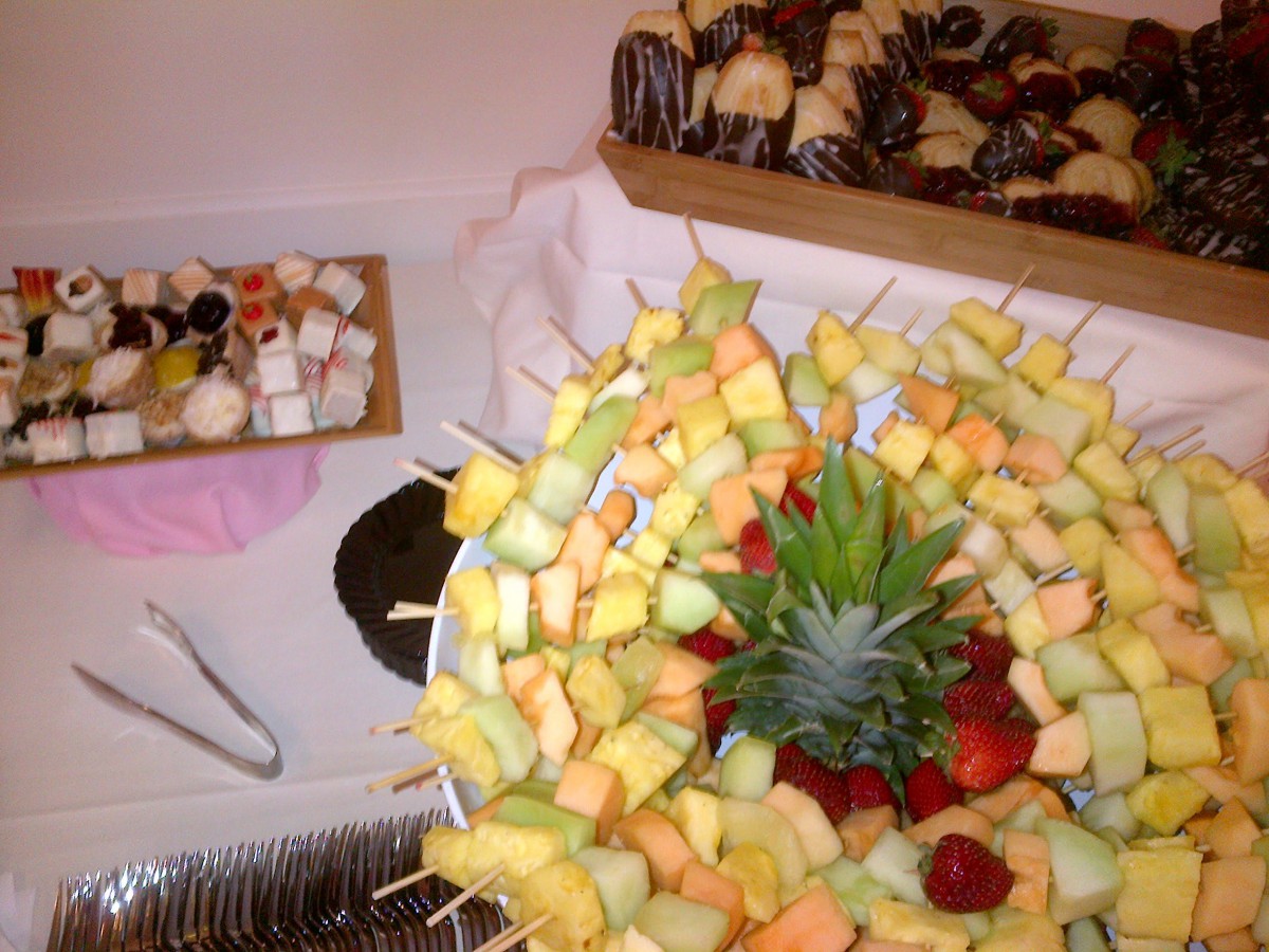A colorful arrangement of fruit skewers and desserts displayed on a buffet table.