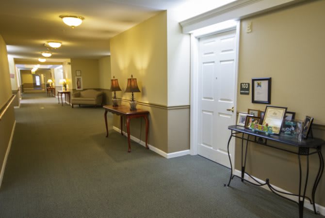 A well-lit hallway with a table and decorative lamps, leading to a white door.
