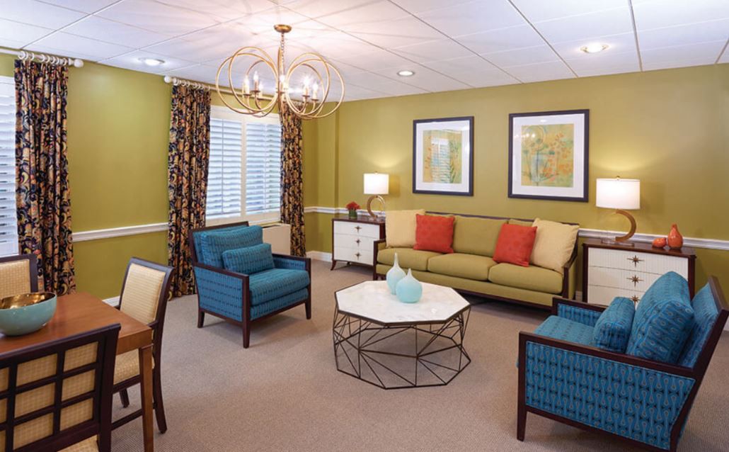 A cozy living room with a modern chandelier, colorful furniture, and wall art.