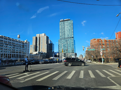 A bustling city intersection with modern skyscrapers under a clear blue sky.