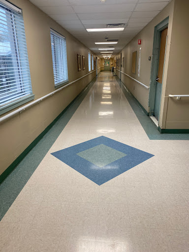 A well-lit corridor with a patterned floor and natural light from the windows.