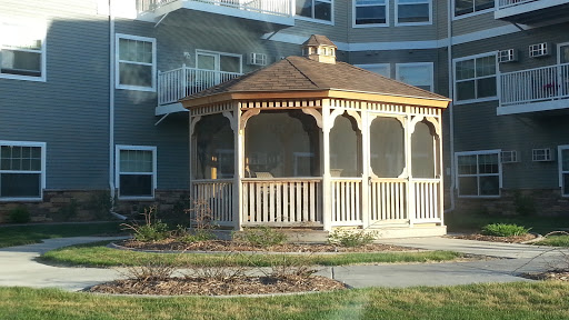 A charming wooden gazebo in front of a residential building.