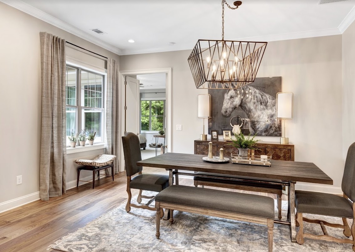 A modern dining room with a wooden table, bench seating, and a stylish chandelier.