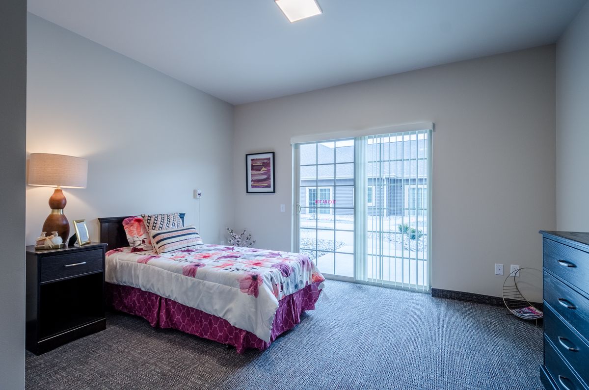 A minimalist bedroom with a bed near a large window allowing natural light.