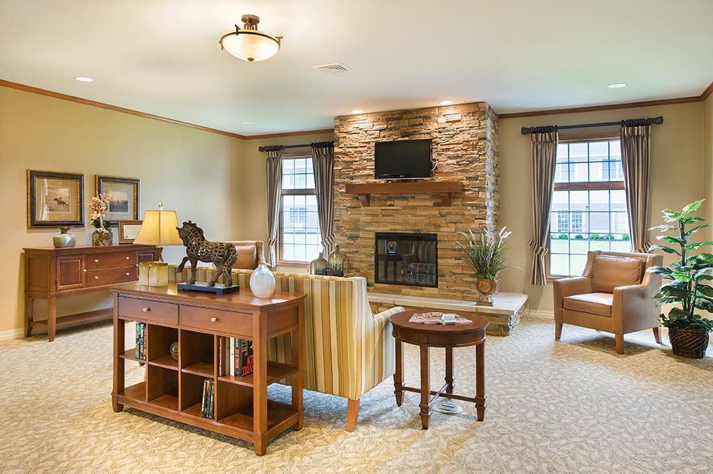 A cozy living room featuring a stone fireplace with a TV mounted above, surrounded by comfortable seating and elegant decor.