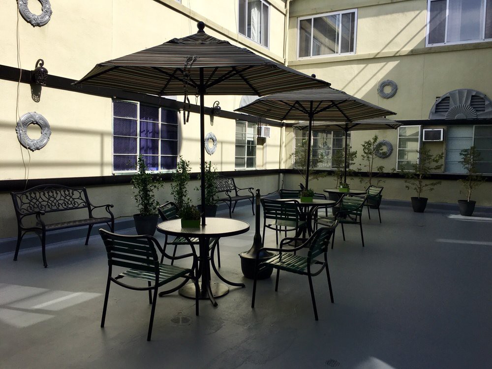 A cozy outdoor patio with tables, chairs, and umbrellas surrounded by a building exterior.