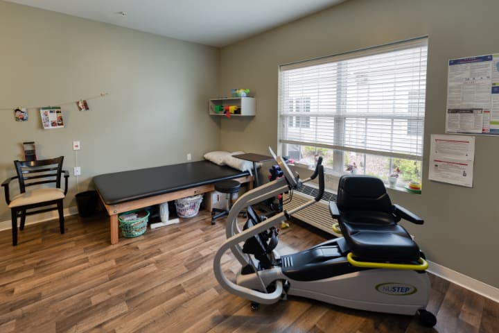 A physical therapy room equipped with a therapy bed and an exercise machine.