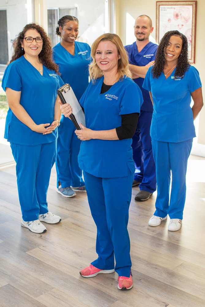 A group of medical staff in blue uniforms standing together in a clinic setting.