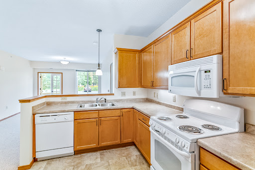 A modern kitchen featuring wooden cabinets, essential appliances, and ample natural light.
