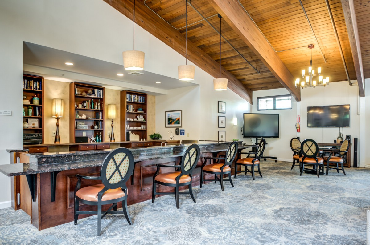 A modern dining area featuring a bar with elegant seating, wooden ceiling, and contemporary decor.