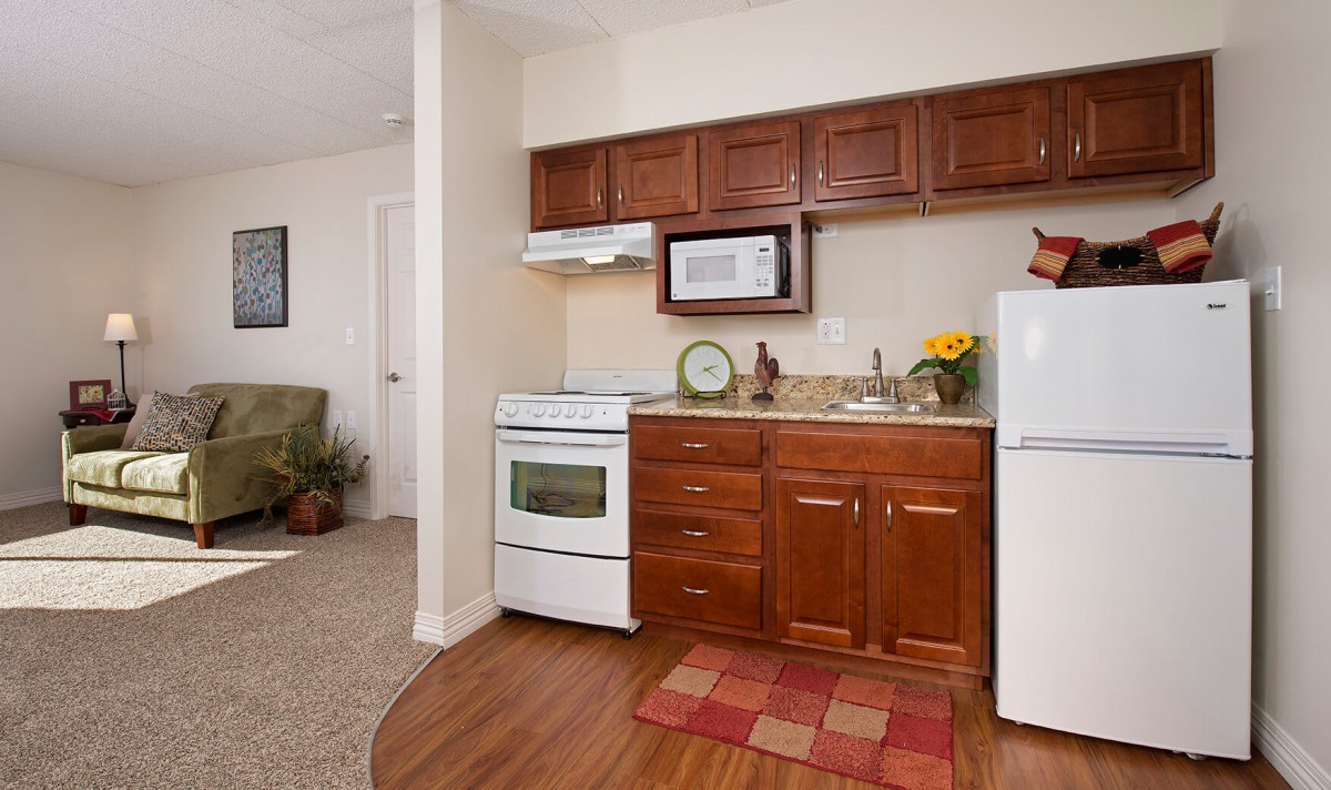 Cozy apartment kitchen with brown cabinets and modern appliances.