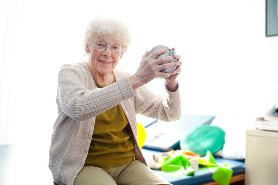 An elderly woman enjoying her knitting hobby.