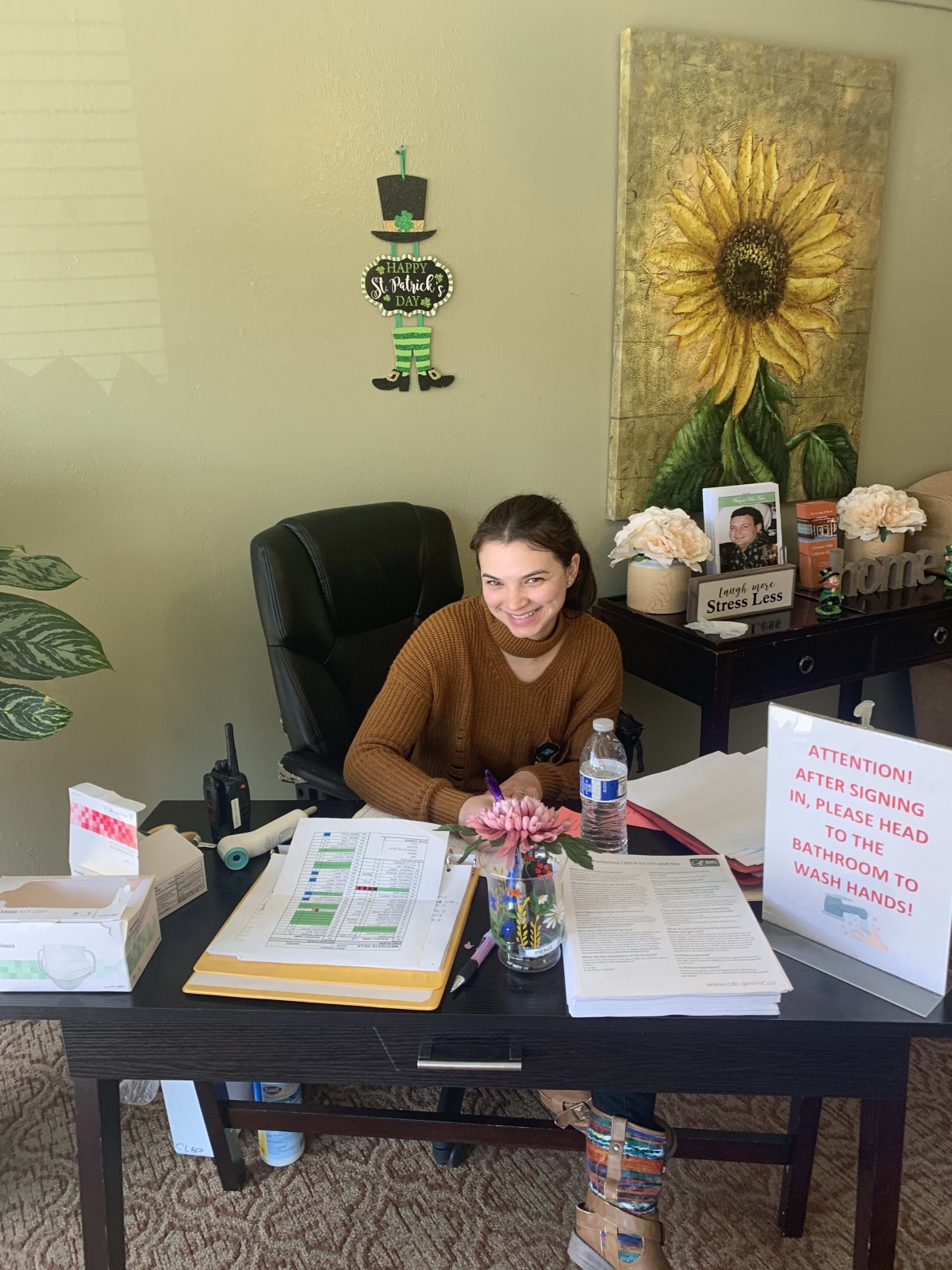 A person sitting at a desk in an office, surrounded by documents and decorations.