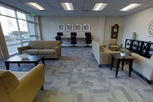 A spacious and modern lounge area designed for relaxation and work, featuring comfortable seating and computer stations.