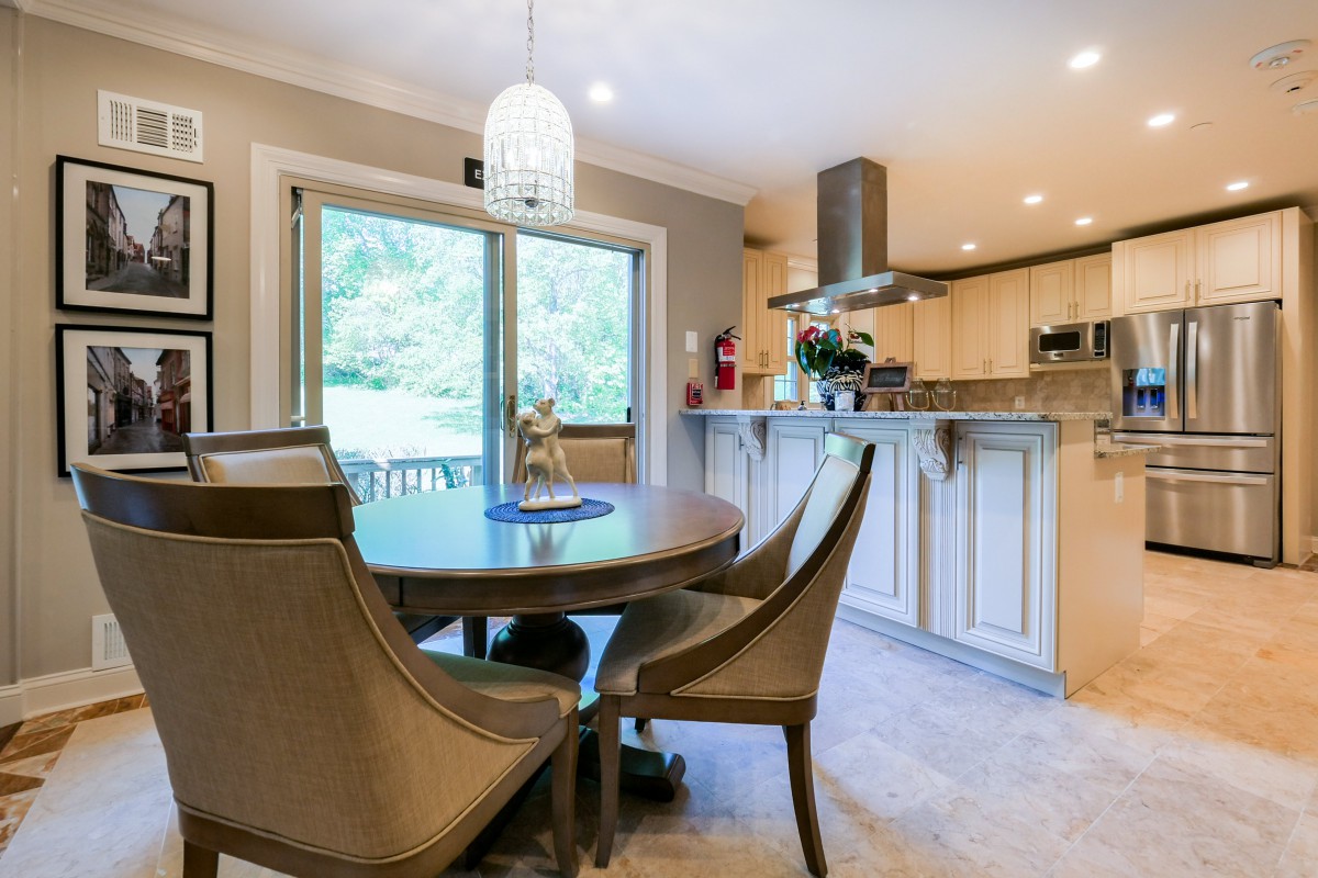 A modern kitchen and dining area with a round table, elegant chairs, and a pendant light.