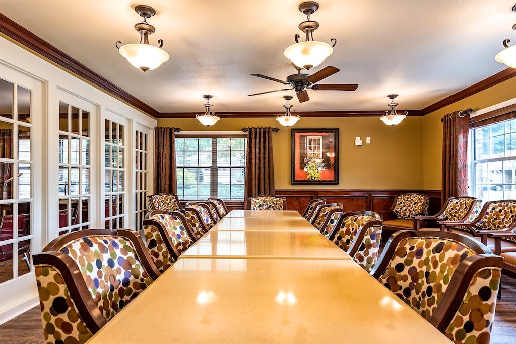 A well-appointed conference room featuring a long table surrounded by upholstered chairs and illuminated by elegant ceiling lights.