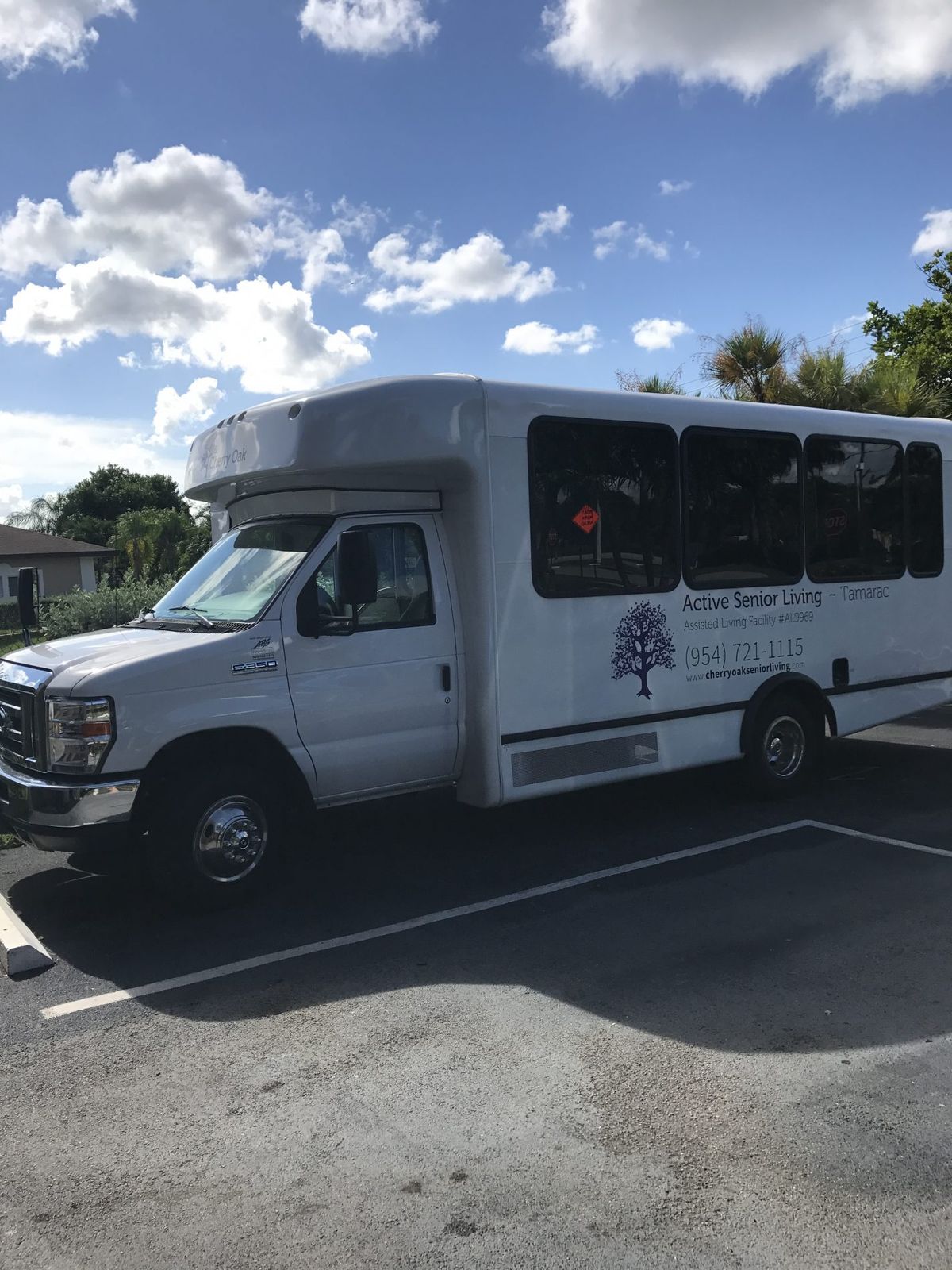 A small shuttle bus parked in a lot under a clear sky.
