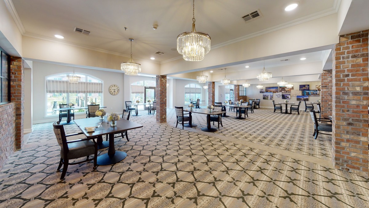 An elegant and spacious dining area with chandeliers and neatly arranged tables and chairs.