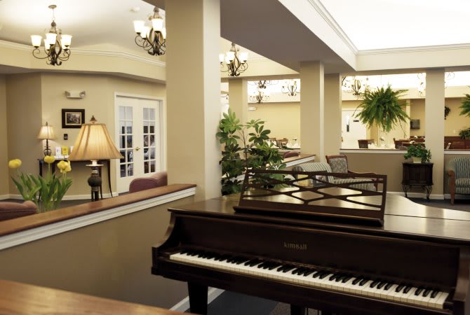 A beautifully decorated living room featuring a grand piano and elegant chandeliers.