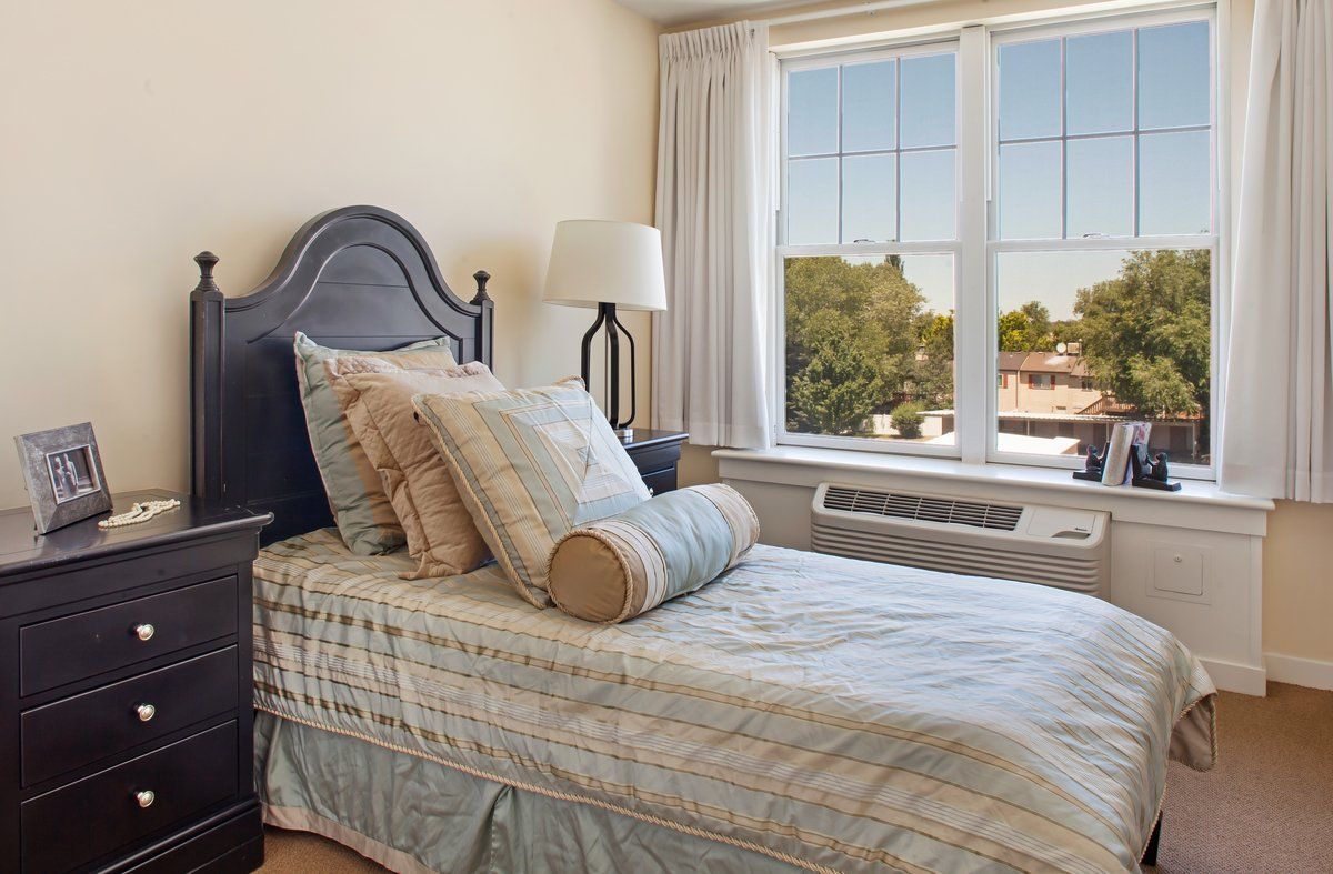 A cozy bedroom with a single bed and large window allowing natural light.