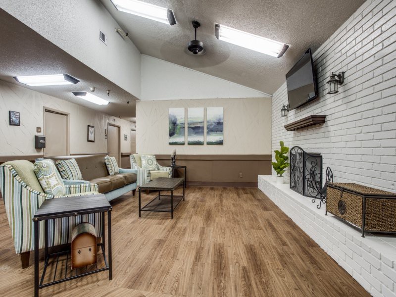 A modern living room with wooden flooring, a fireplace, and a wall-mounted television.