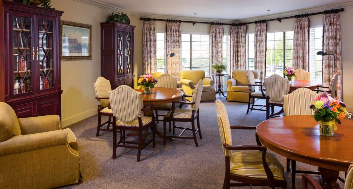 A cozy living room with a dining area, featuring elegant furniture and large windows.