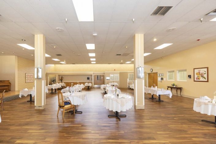An empty dining area with neatly arranged tables and chairs on a wooden floor.