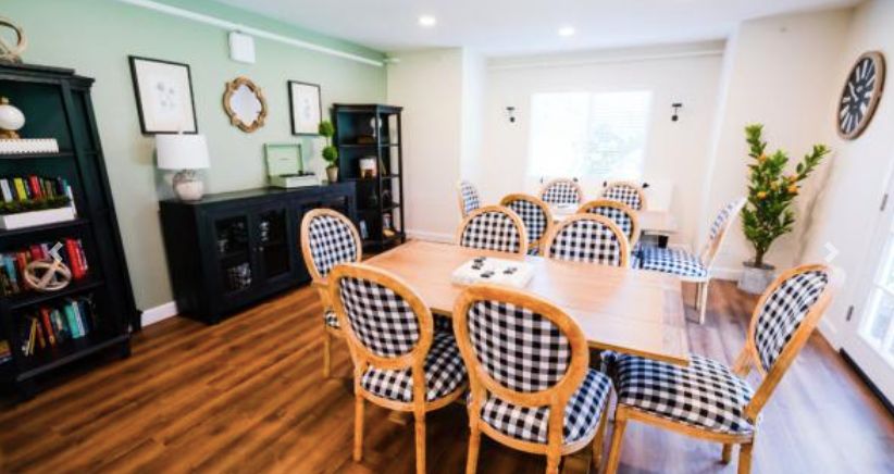 A modern dining room with checkered chairs and a large wooden table.