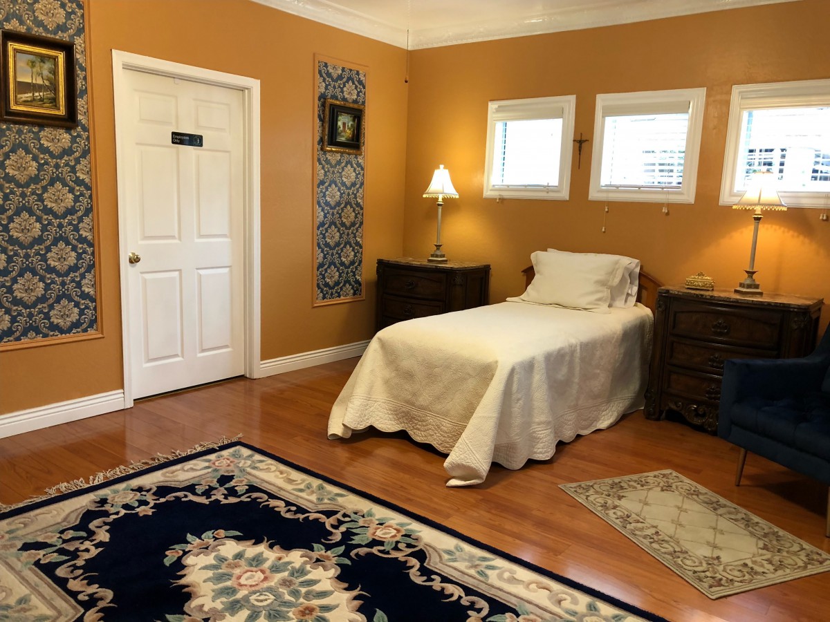 A cozy bedroom with a single bed, warm-colored walls, and a decorative rug.