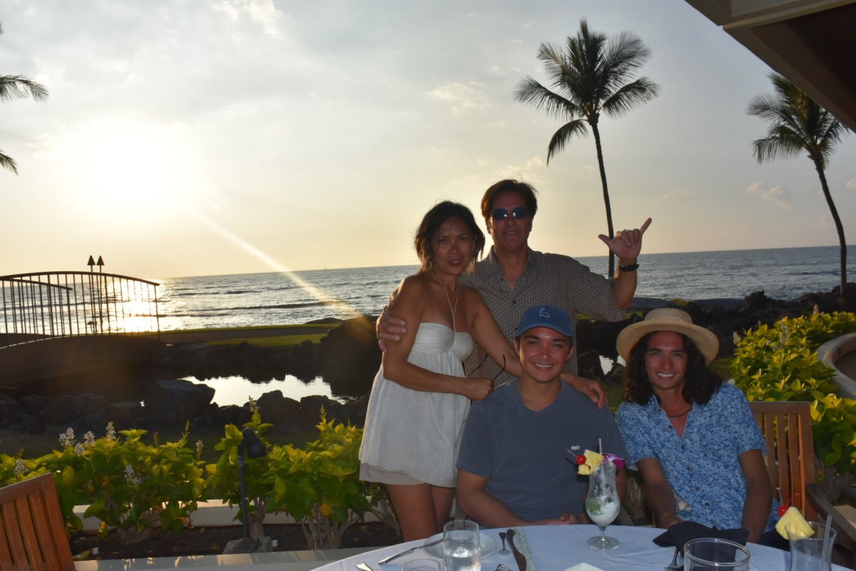 A group of people enjoying a sunset dinner by the beach.