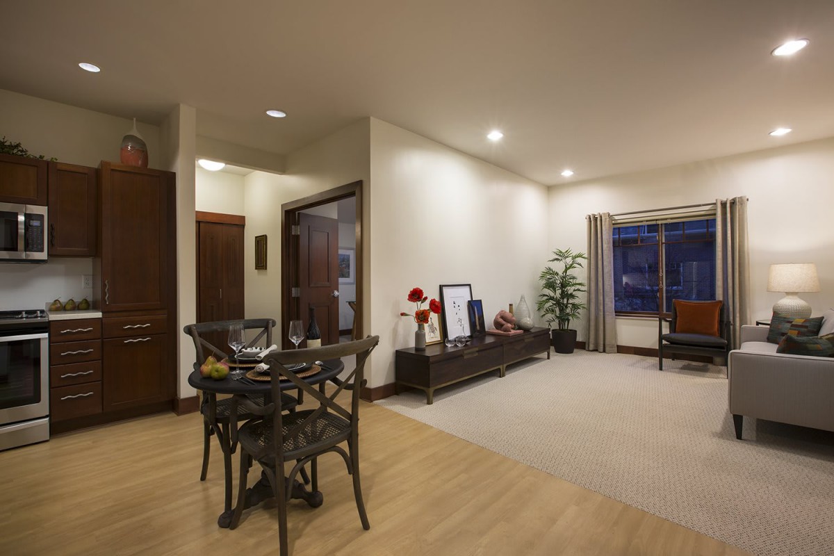 A modern living room with a dining area, featuring wooden flooring and contemporary furniture.