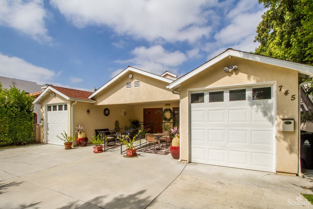 A suburban house with a driveway and garage under a partly cloudy sky.