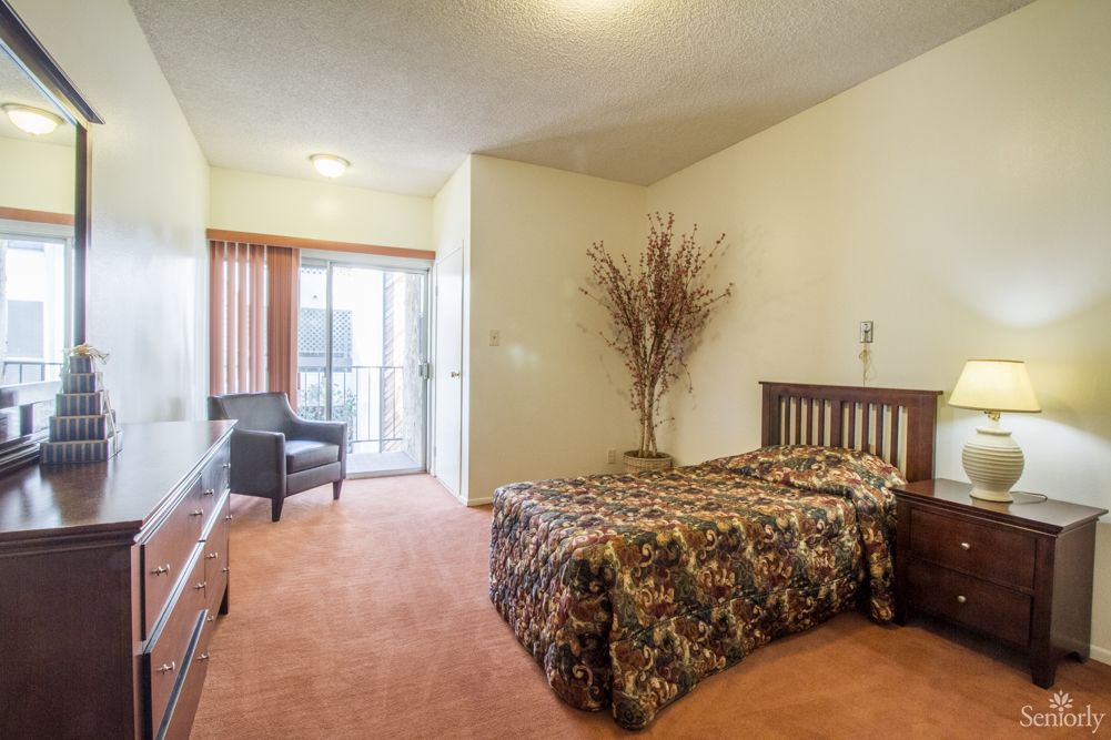 A cozy bedroom with a single bed, patterned bedding, and access to a balcony.