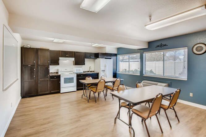 A spacious kitchen and dining area with tables, chairs, and modern appliances.