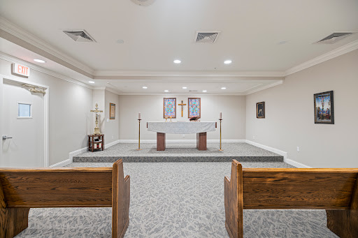 A serene chapel space featuring a central altar with wooden pews for worship.