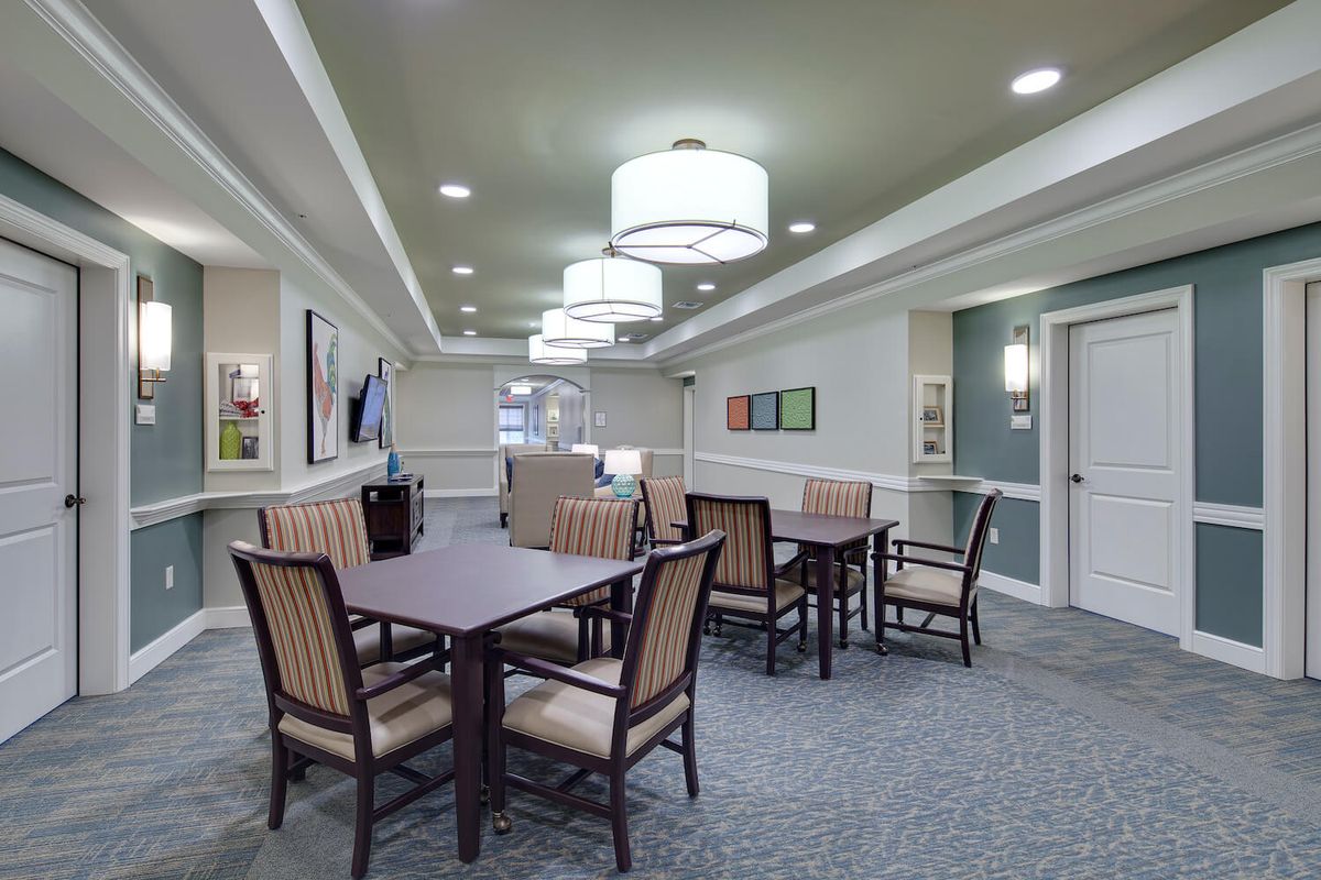 A modern dining area with multiple tables and chairs, well-lit by contemporary lighting fixtures.