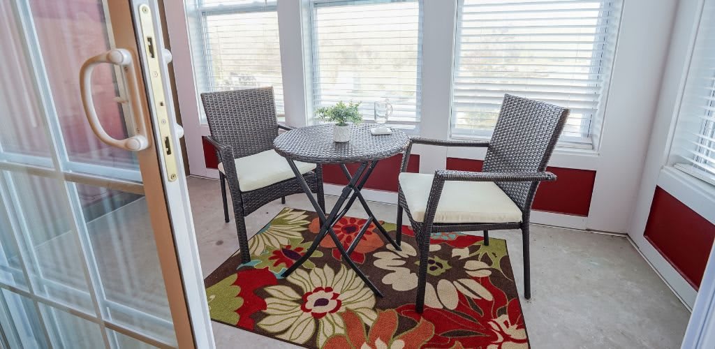 A cozy indoor seating area with a small round table, two chairs, and a colorful floral rug.