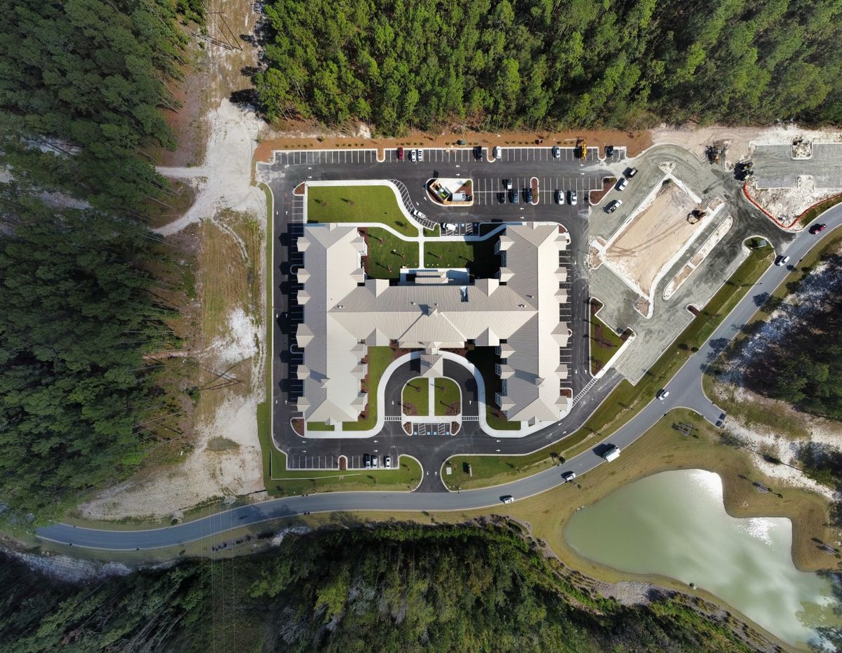 Aerial view of a building complex surrounded by trees and parking lots.