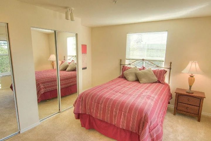 A cozy bedroom with a neatly made bed and mirrored closet doors.