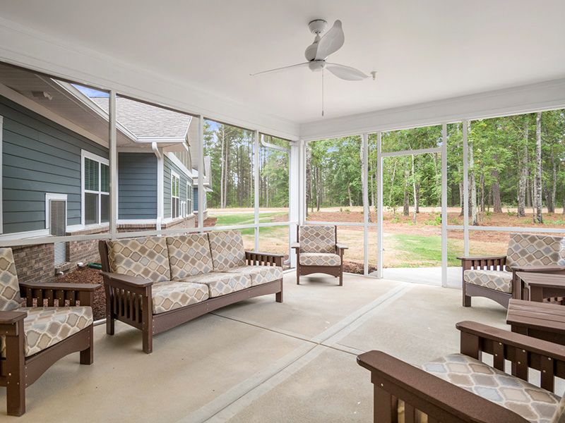 A cozy sunroom with comfortable seating and a ceiling fan overlooking the backyard.