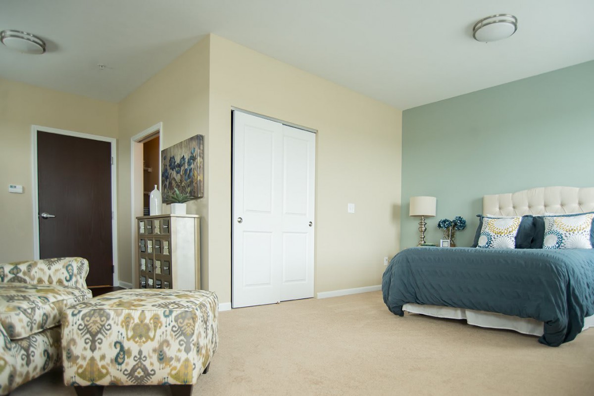 A modern bedroom with a neatly made bed, stylish decor, and soft lighting.