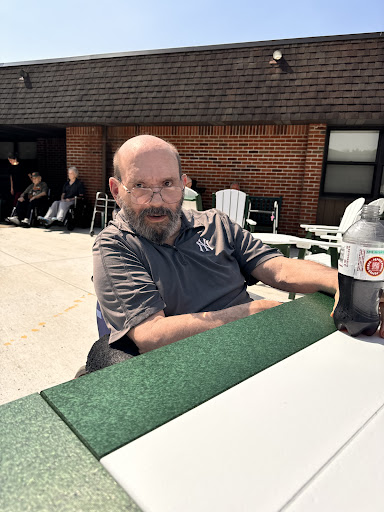 A man enjoying a sunny day outdoors, seated at a table.