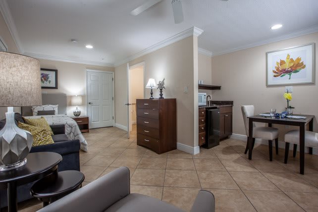 A cozy living space featuring a dining area and a bedroom, with warm lighting and elegant decor.